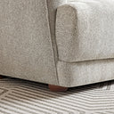 Close-up of the Stacey cream luxury fabric sofa showcasing its textured woven upholstery, curved armrest seam, and round wooden leg resting on a geometric rug.
