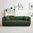 Green luxury fabric sofa with rounded arms and two matching accent pillows on a geometric patterned rug in an elegant living room with white wall molding and a fireplace mantel.
