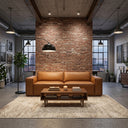 Vanna 93-inch mid-century modern cognac brown vegan eco-leather sofa centered in an industrial loft living room against an exposed brick wall, with a wooden coffee table, patterned area rug, and arched floor lamp.